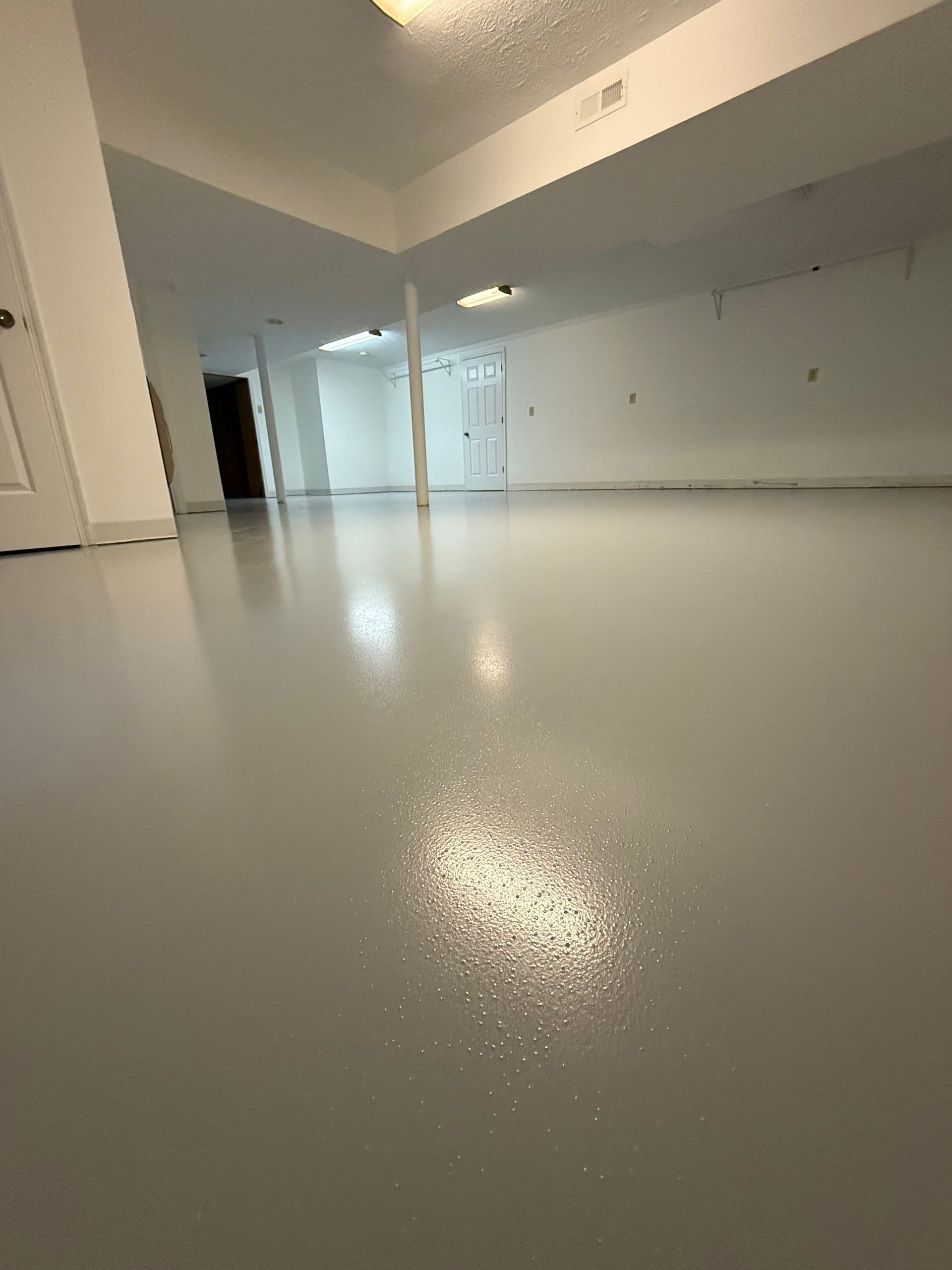 Empty glossy white room with reflective floor and ceiling lights, viewed from a low angle
