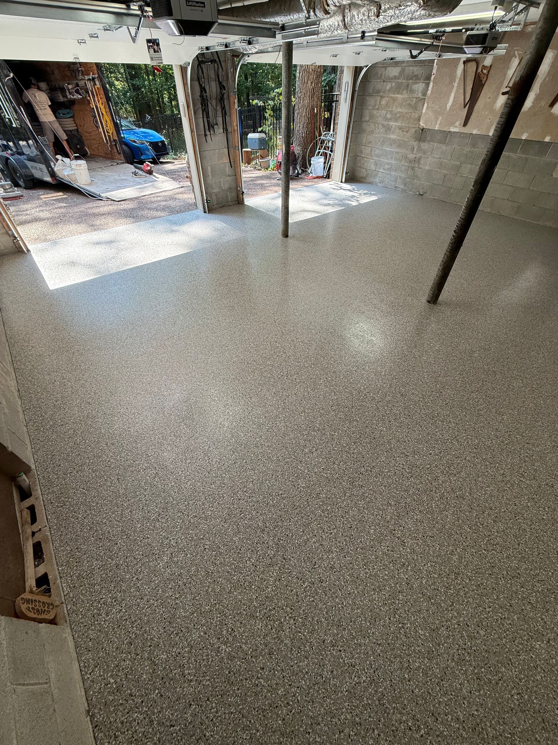 Small room with a speckled floor, exposed ceiling, and bright outdoor light beyond an opening