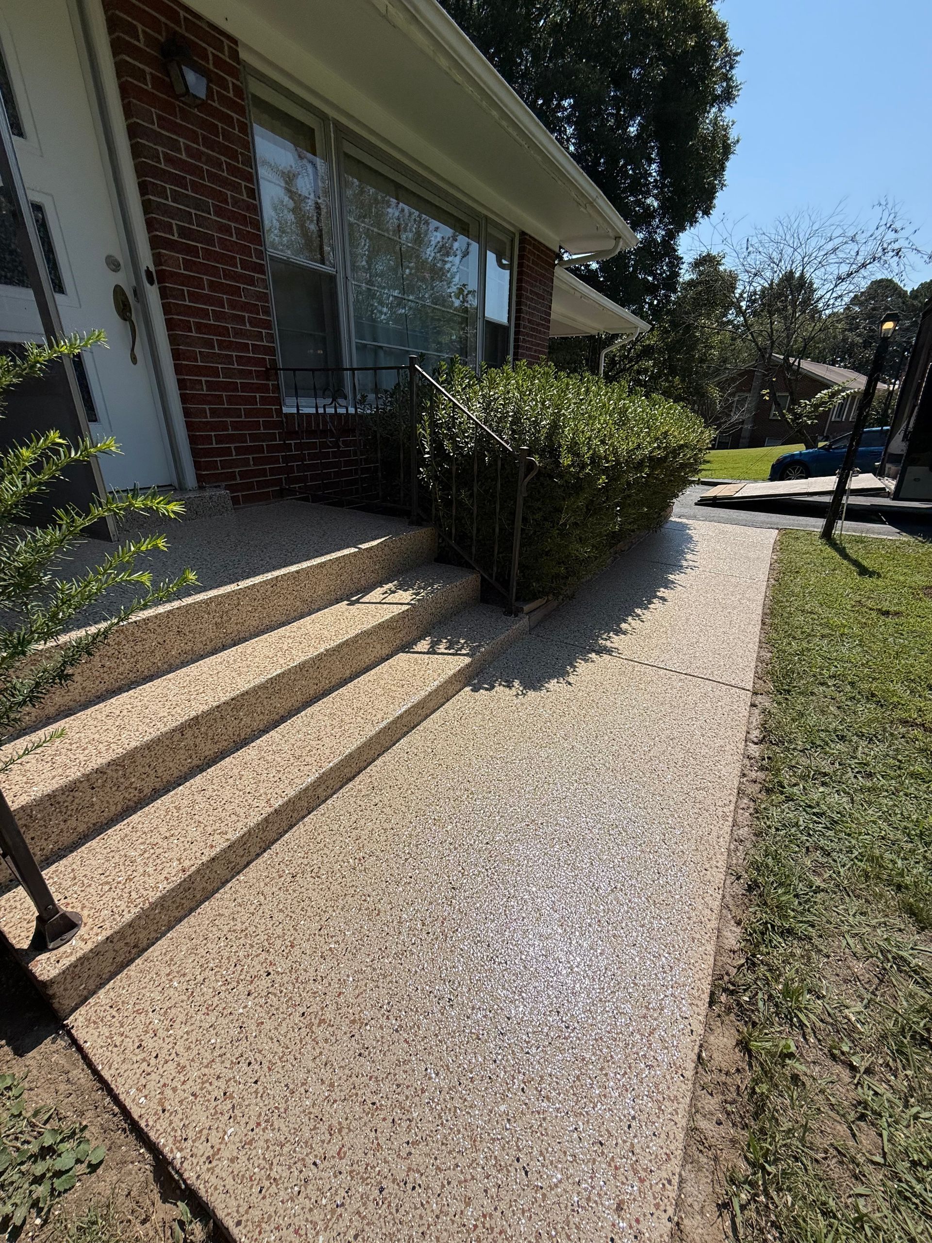 House entrance with brick steps, white porch, and gravel walkway beside a green lawn