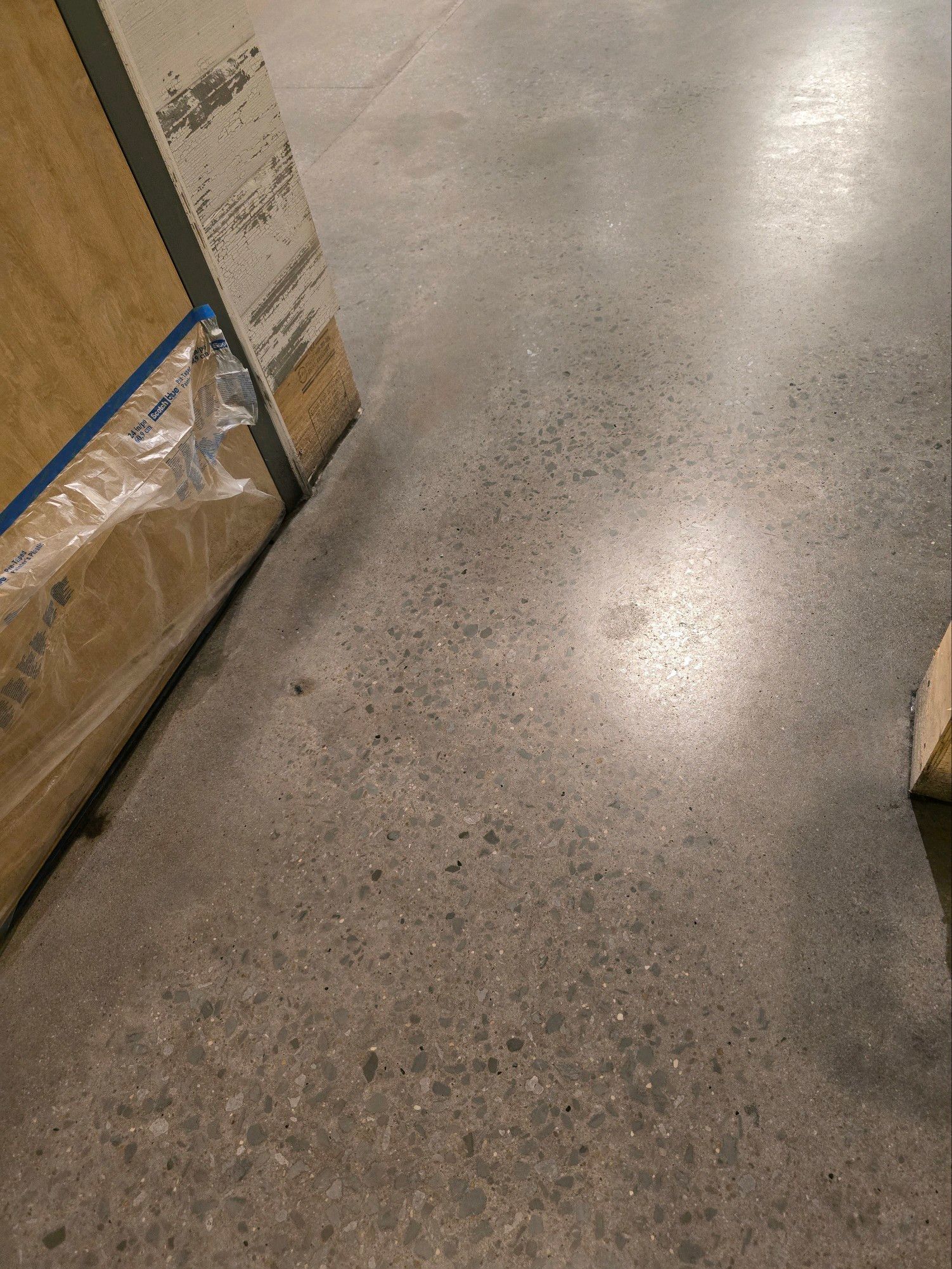 Concrete floor with a cardboard box on the left and a glimpse of wood on the right.