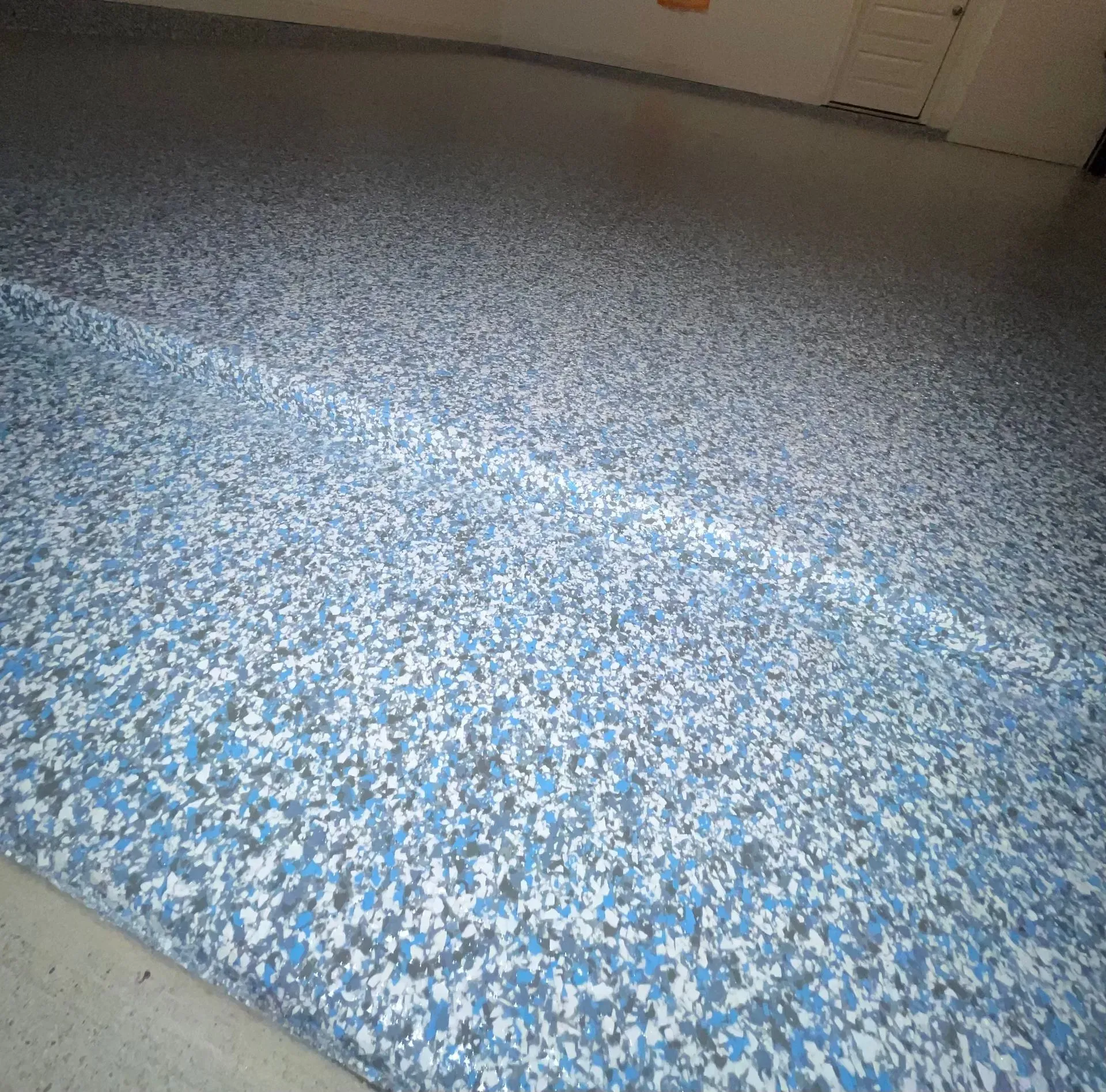 Blue, white, and gray speckled epoxy floor in a garage.
