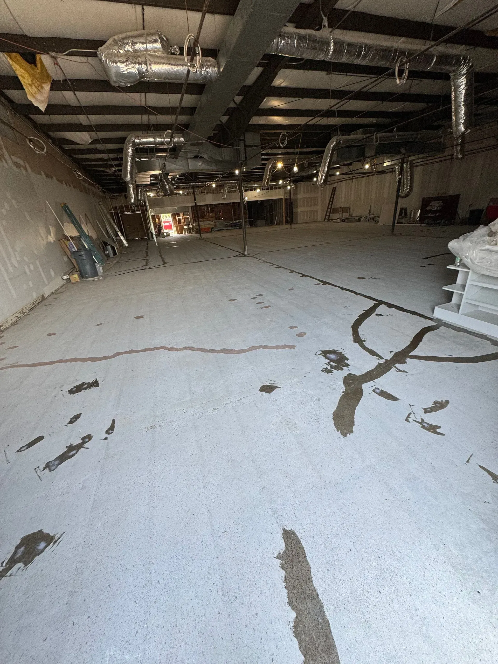 Empty warehouse interior with concrete floor, ductwork, and exposed ceiling.