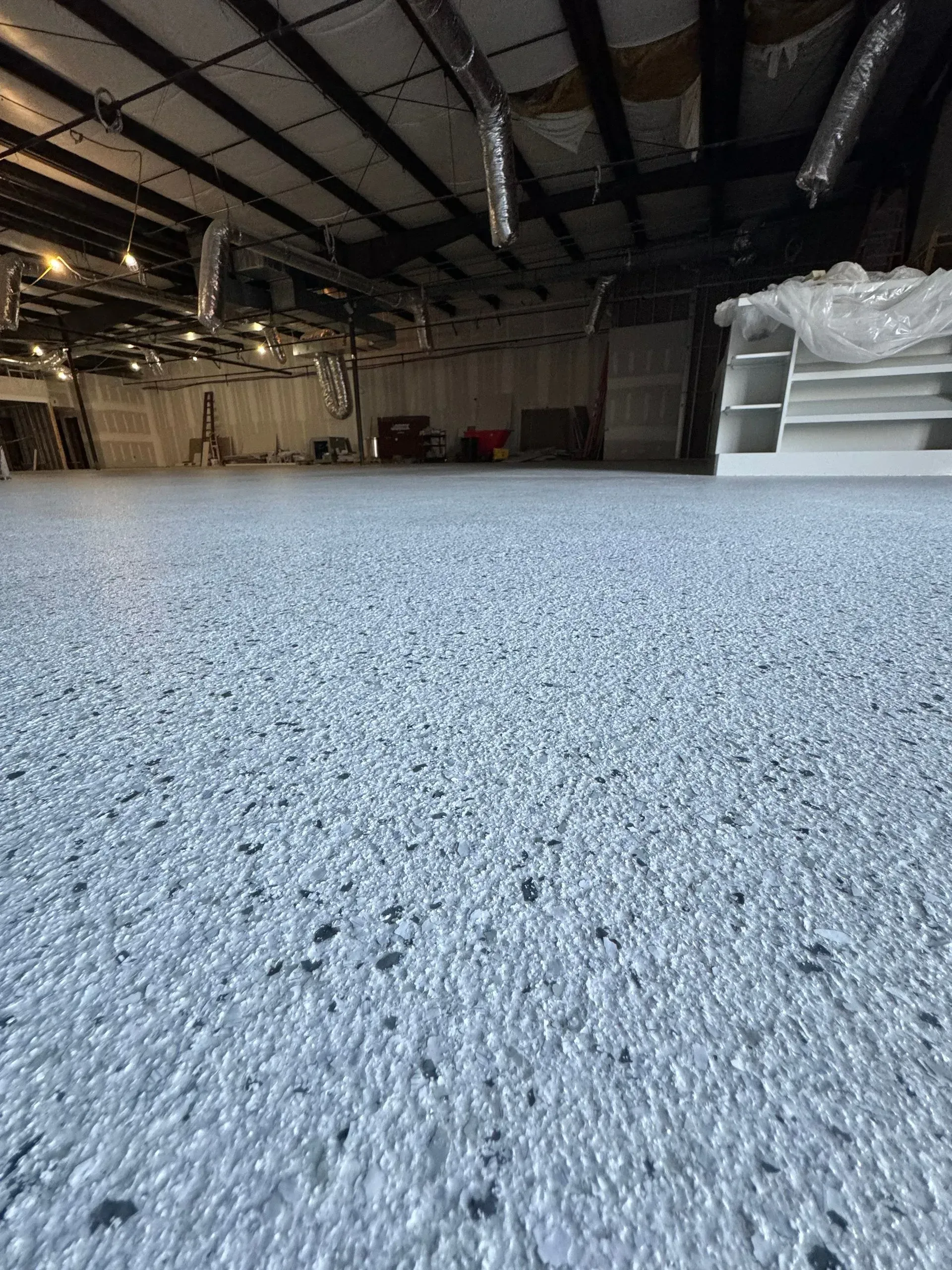 A wide shot of a spacious room with a light gray speckled epoxy floor.