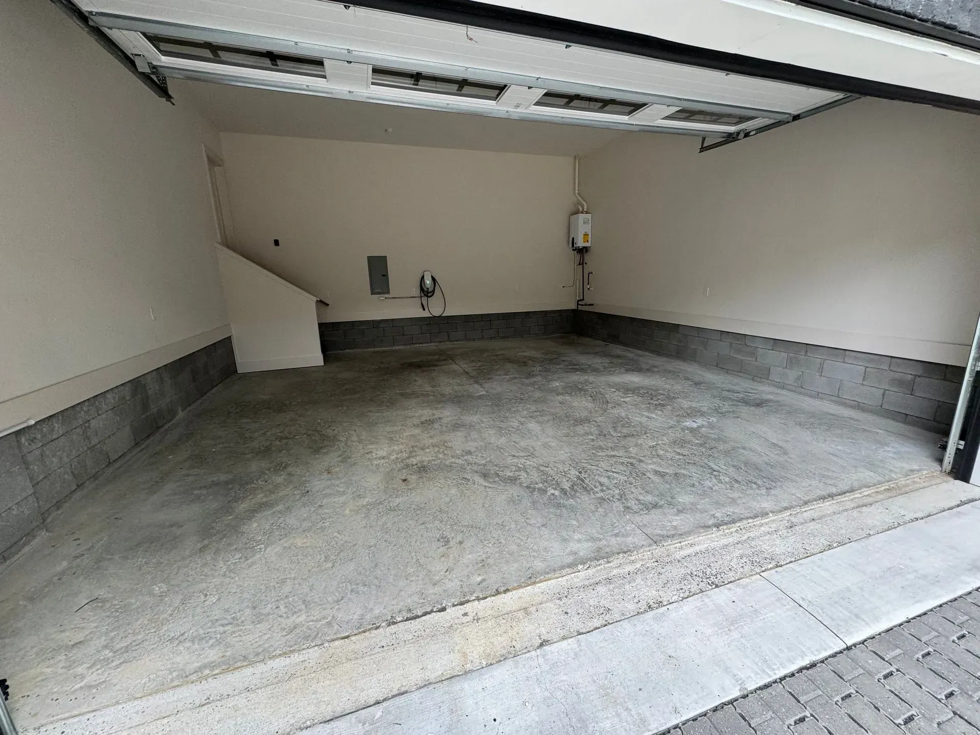Empty garage with concrete floor and light beige walls.