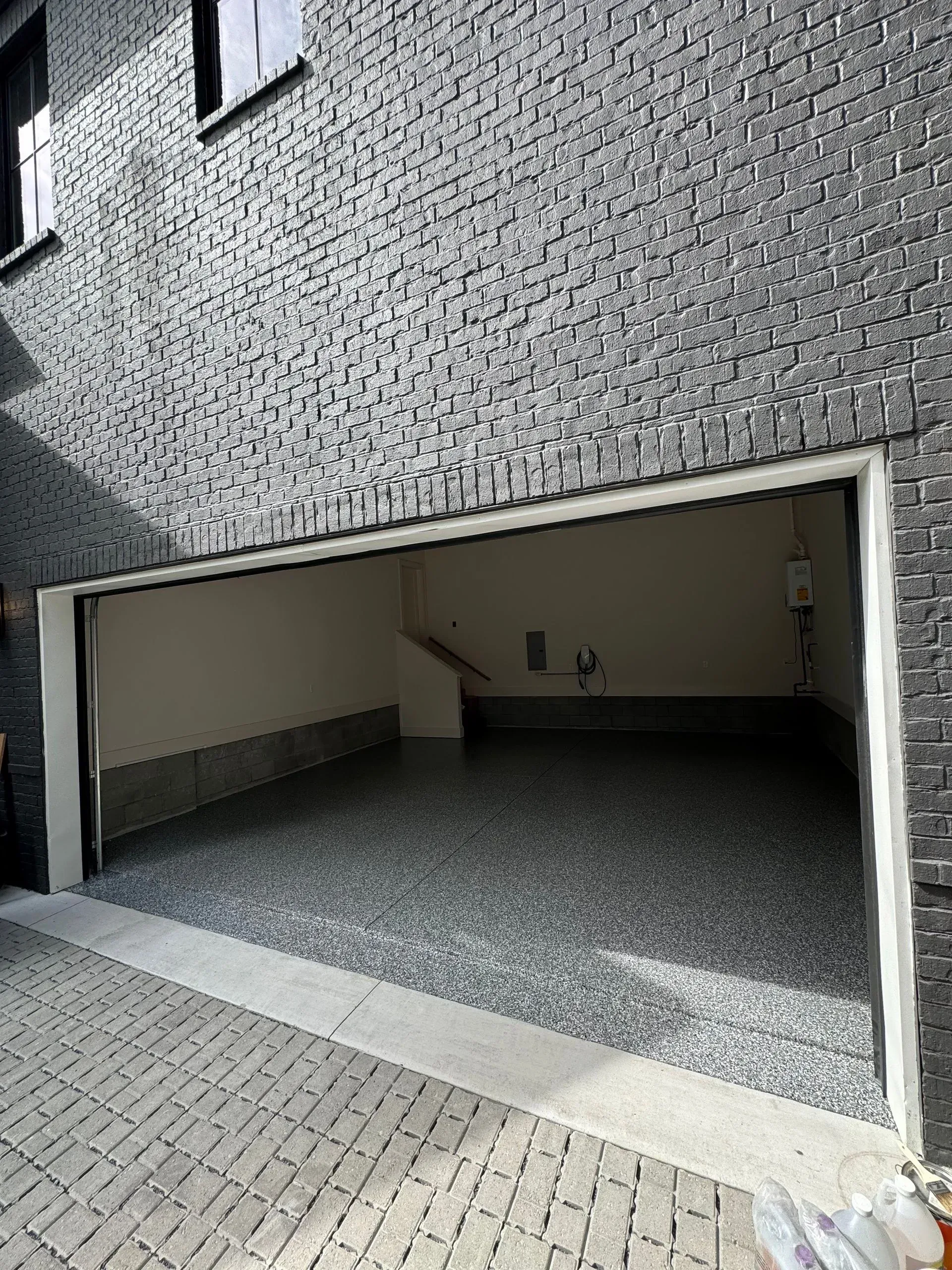 Open garage with a speckled floor and gray brick exterior.