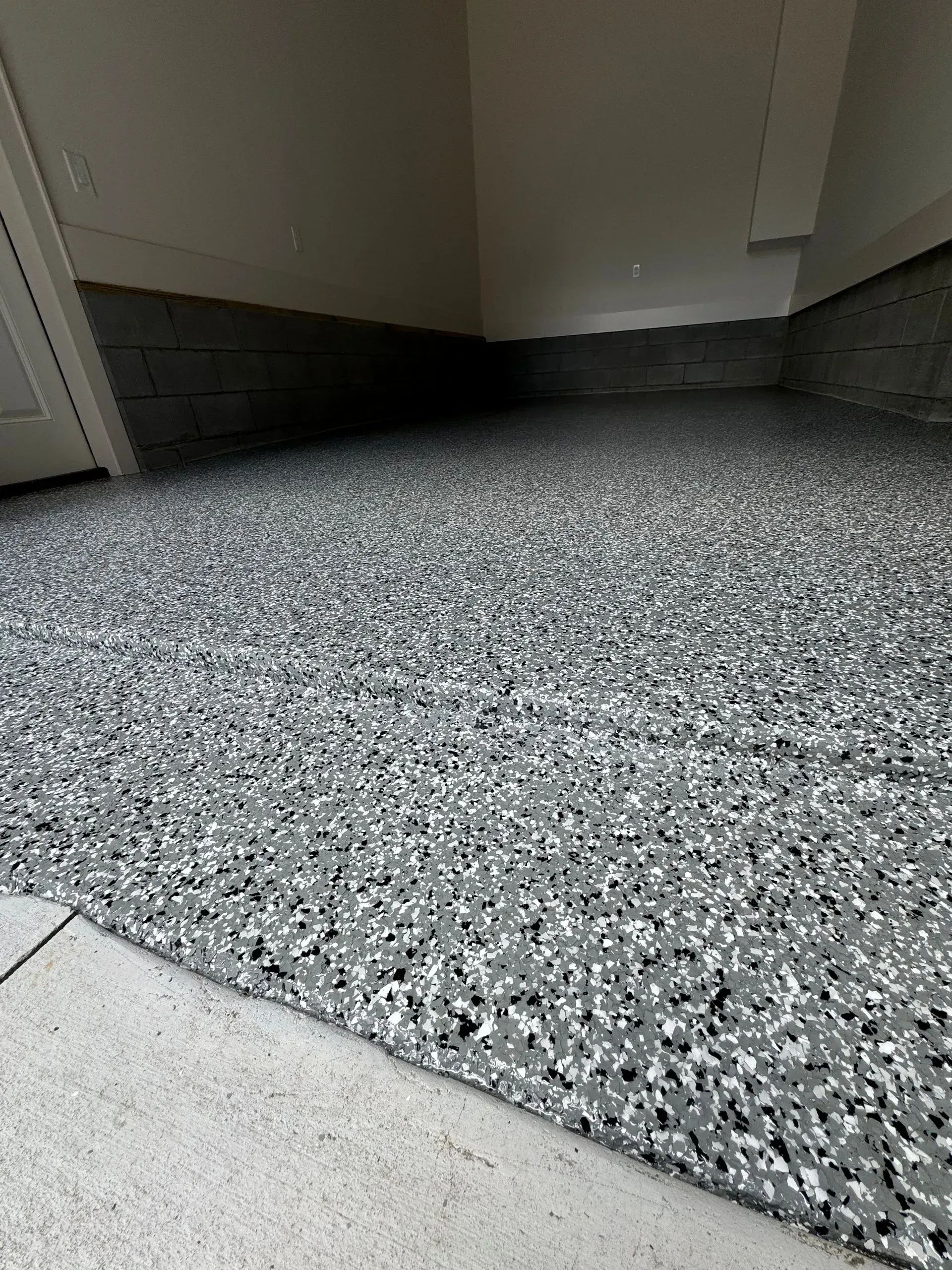 Gray speckled epoxy floor in a room with white walls and a concrete threshold.