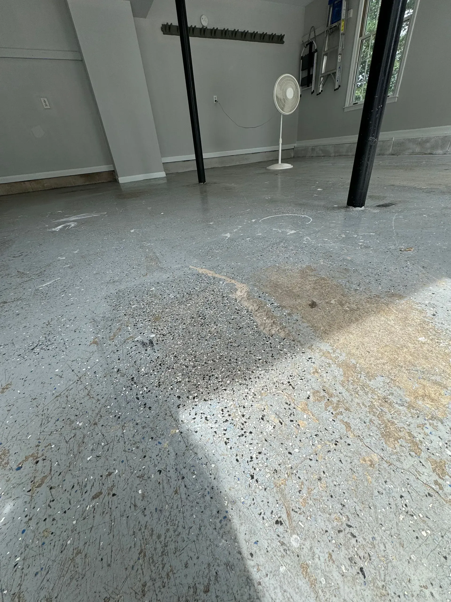 Garage floor with a pile of debris in the center, gray speckled concrete.