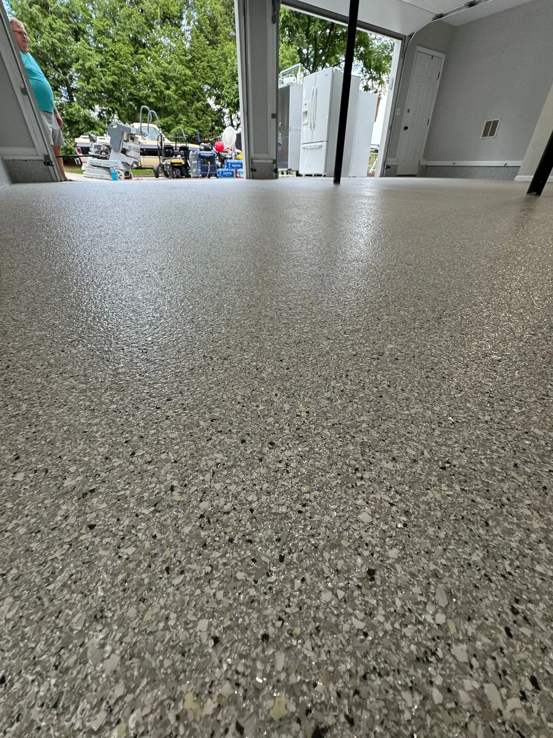 Epoxy-coated concrete floor with scattered chips reflecting light. Open doors lead to outdoor area.