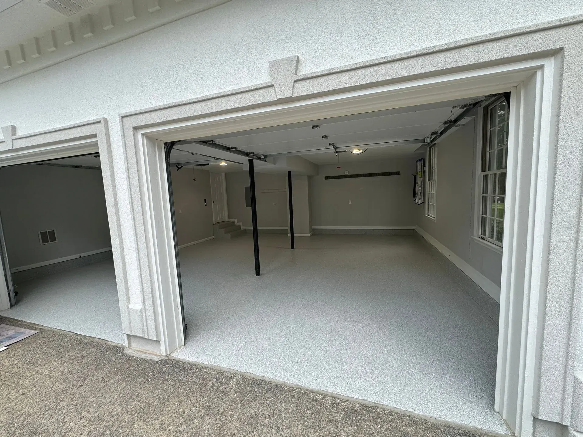 Open, newly painted garage with epoxy floor. Gray walls and trim, black beams.