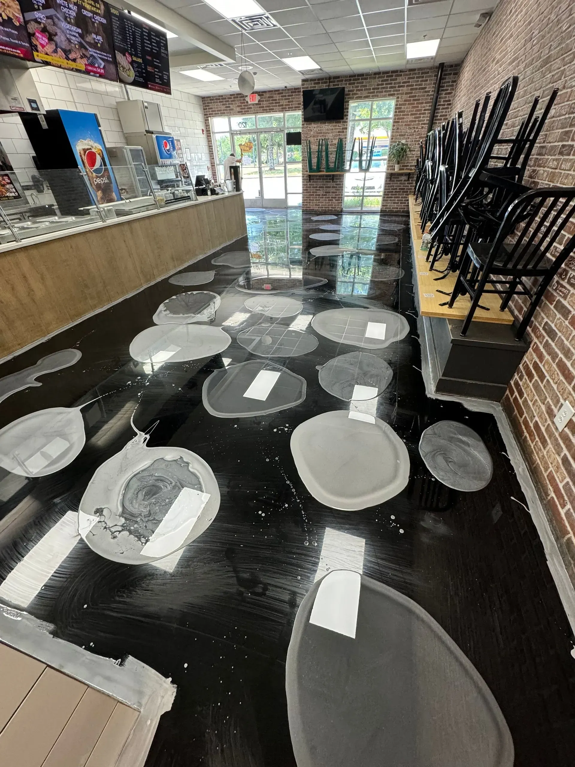 Black floor with unevenly shaped gray patches, some with white paper tags, in a store.