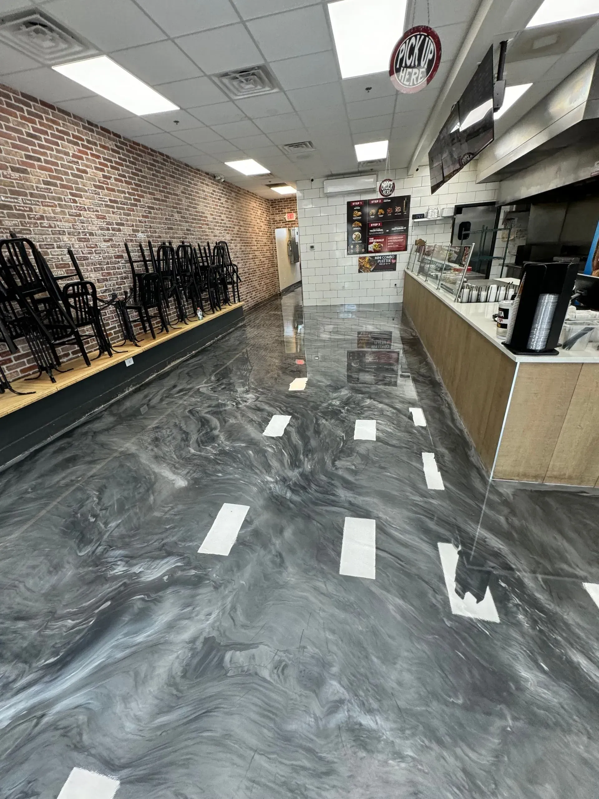 Shiny gray and white swirled floor in a commercial space, with chairs stacked and a counter on the right.
