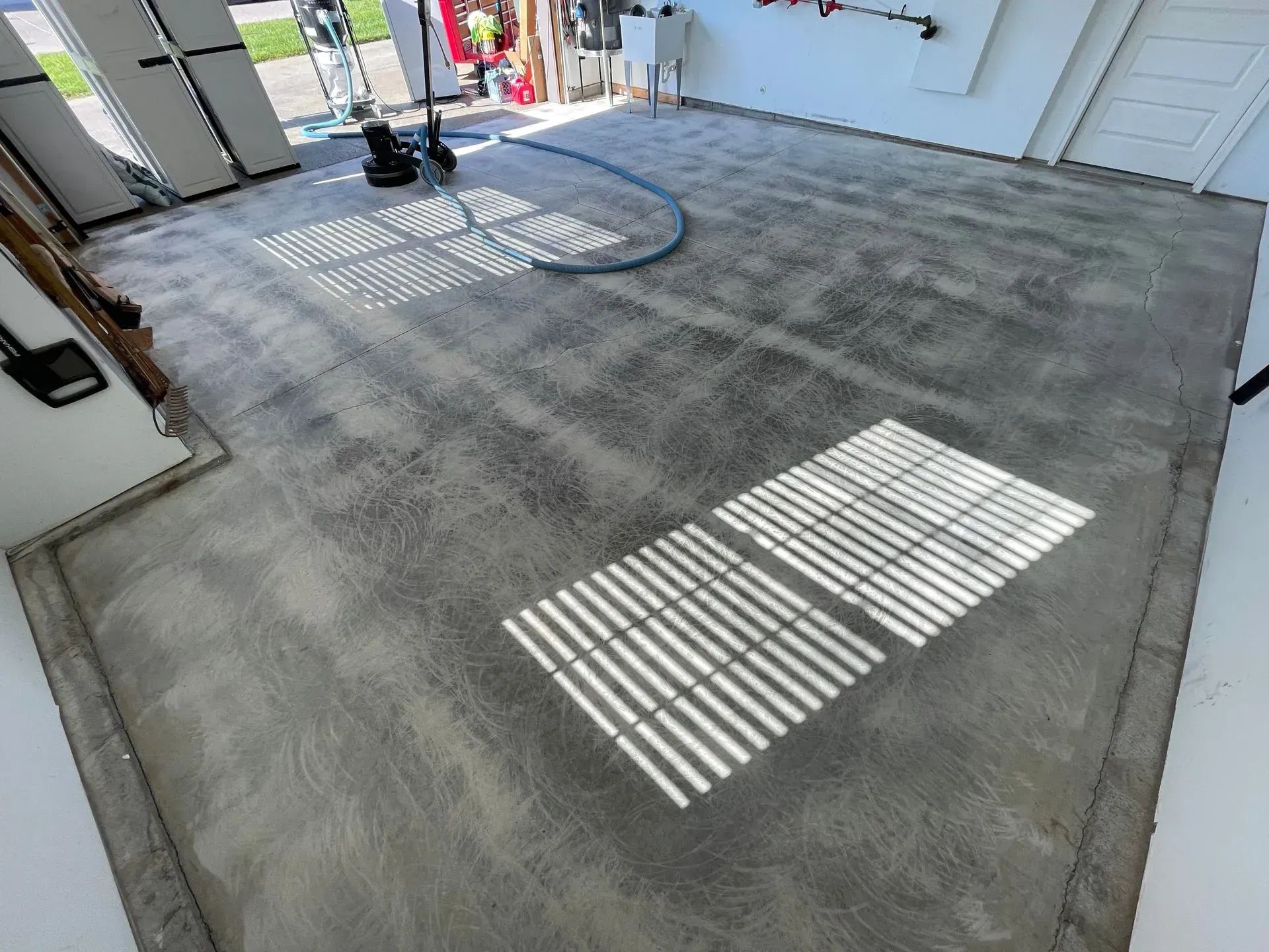 A newly surfaced garage floor. Grey concrete with two rectangles of light from a window.