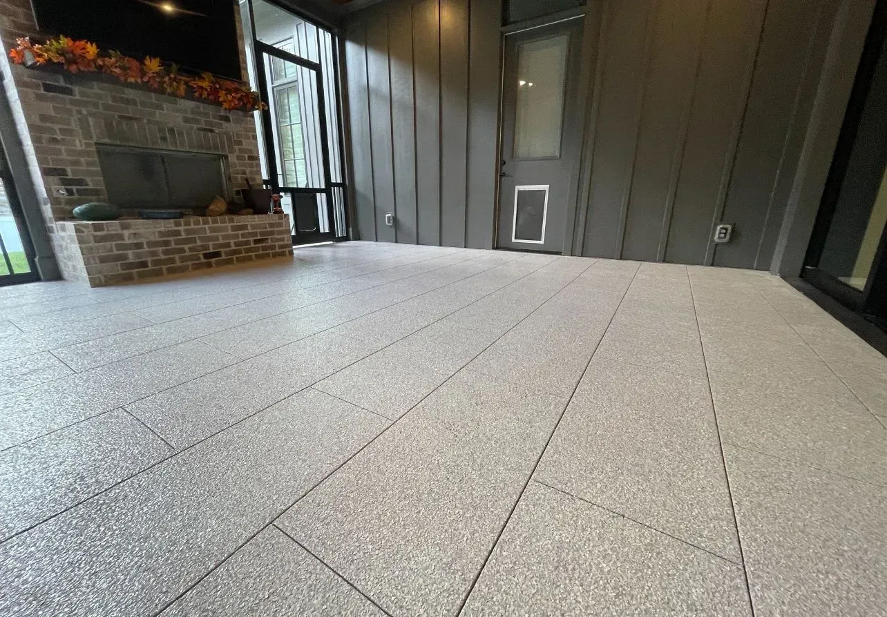Grey speckled tile patio with fireplace and door in a screened porch.