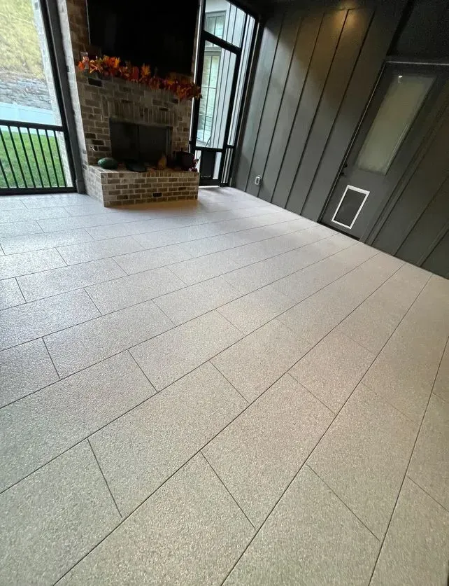 Light gray tiled floor in sunroom, brick fireplace, and dark gray walls.