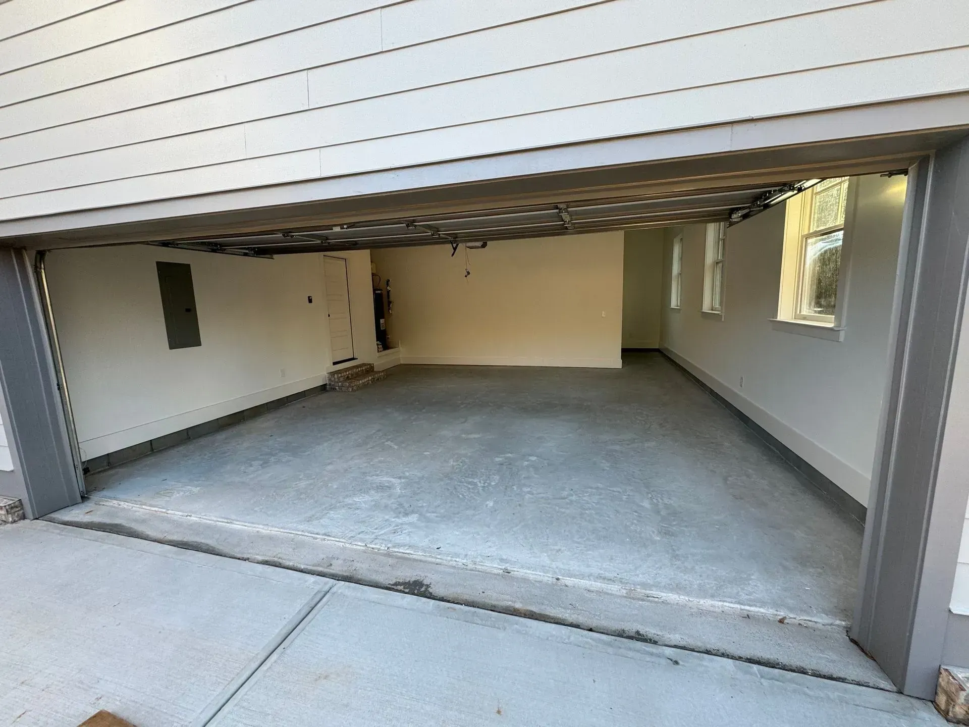 Open garage interior: gray concrete floor, light-colored walls, three windows on the right.