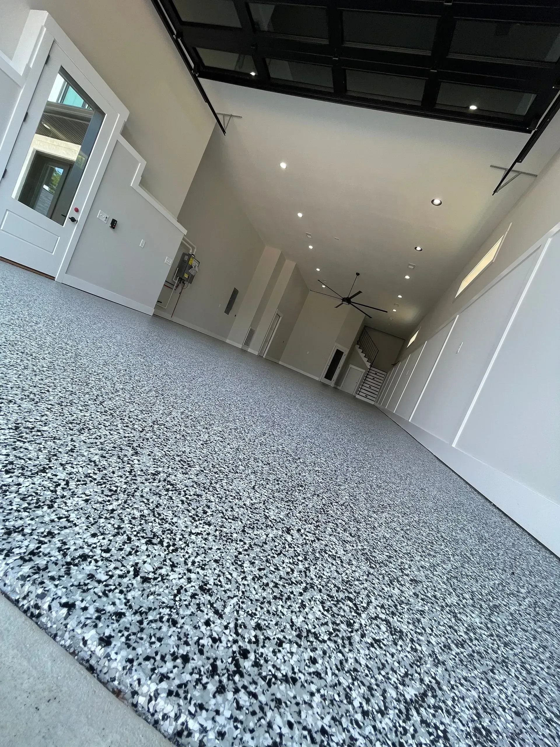 Garage with epoxy floor. White walls, glass ceiling, and open door on the left.