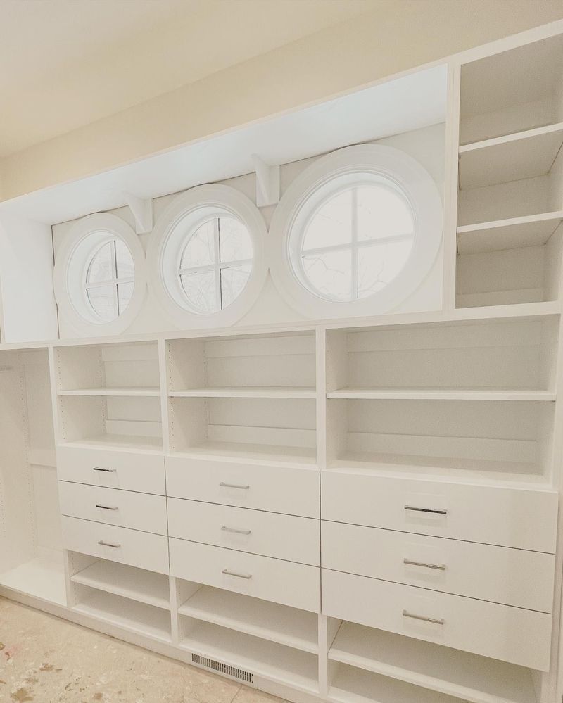White closet built-ins with shelves, drawers, and porthole windows.