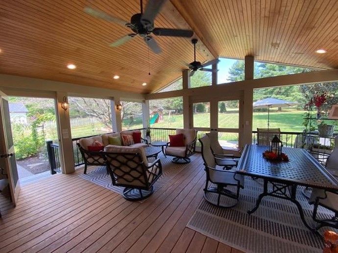 Covered outdoor patio with seating and ceiling fans, overlooking a grassy yard.