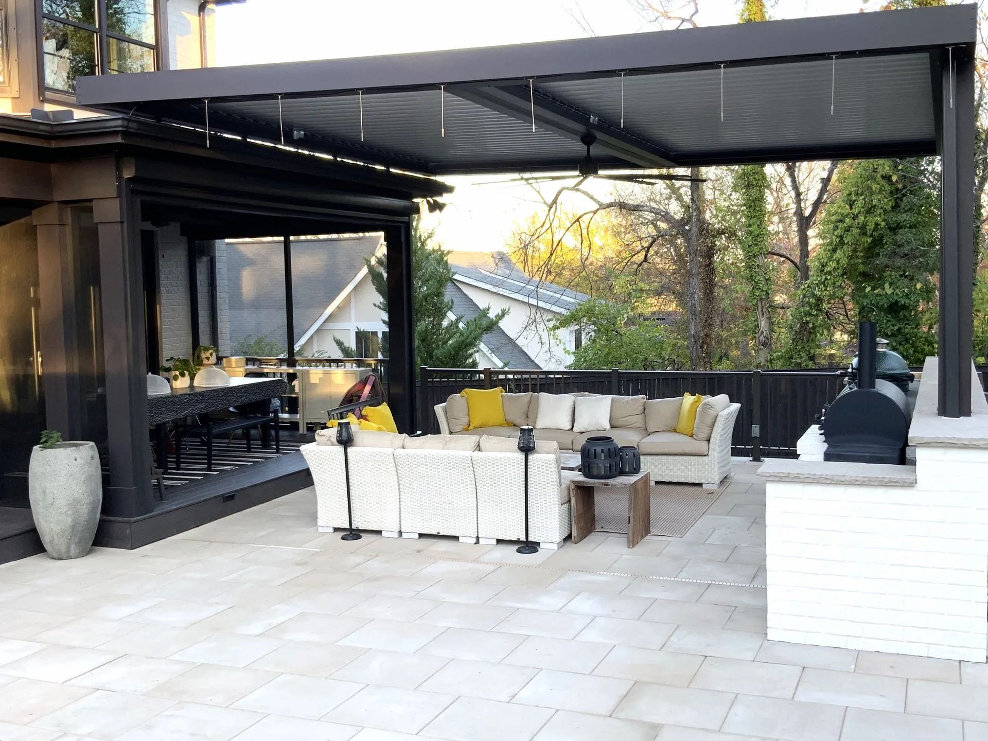 Outdoor patio with black pergola, seating, and grill.