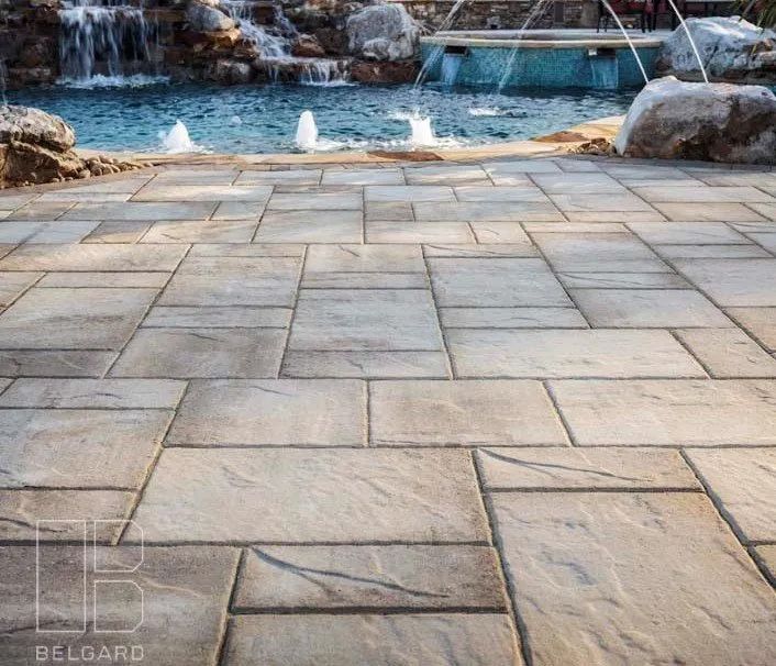 Stone patio with pool, waterfall, and fountains.