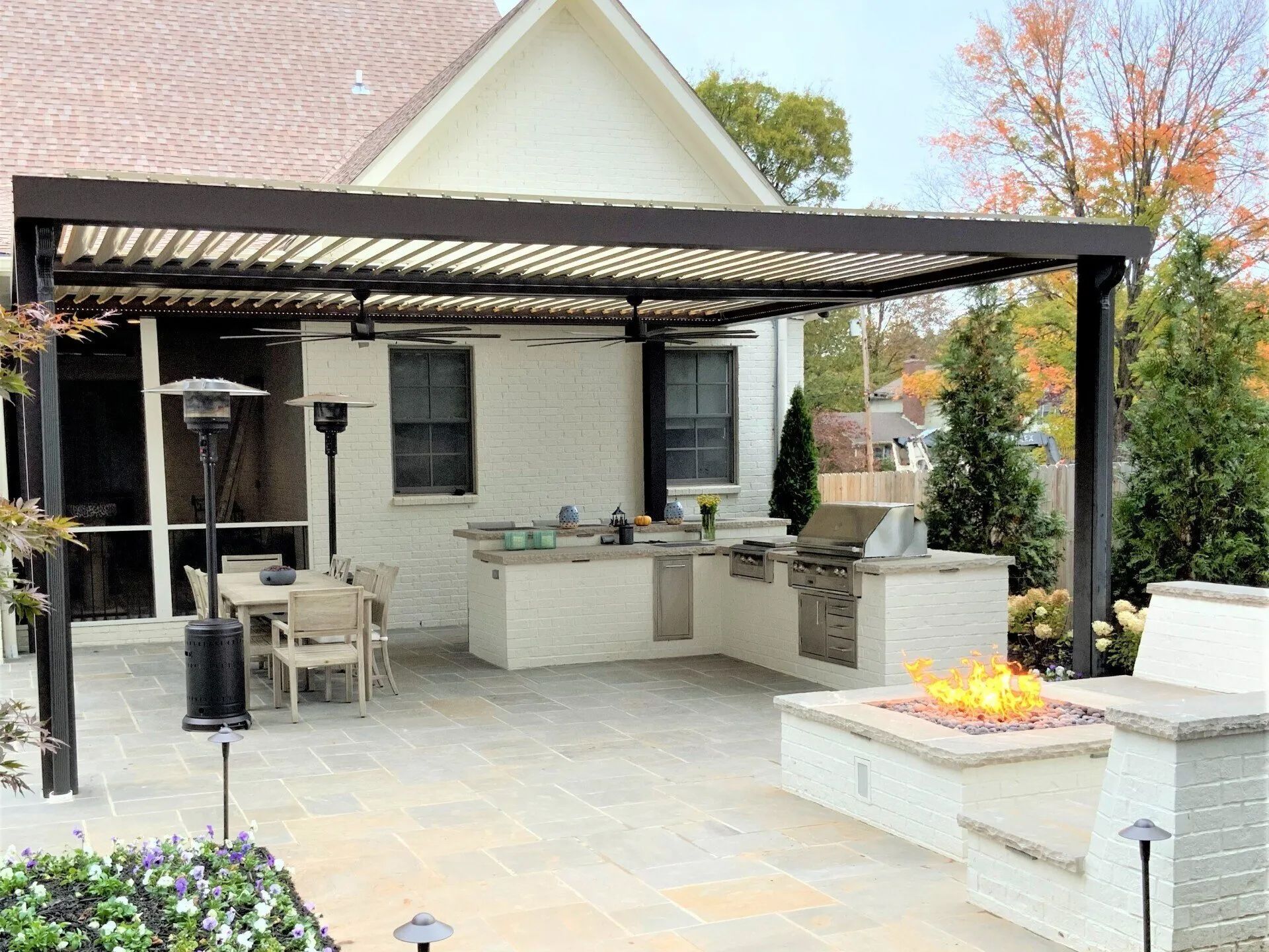 Outdoor kitchen and patio with pergola, grill, and fire pit.