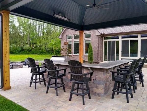Outdoor bar with seating under a dark canopy; brick home in the background.