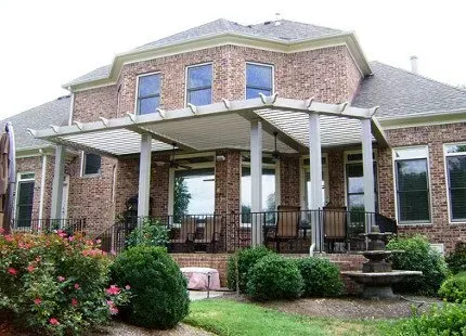 A brick house with a pergola-covered patio. Several windows and doors are visible.