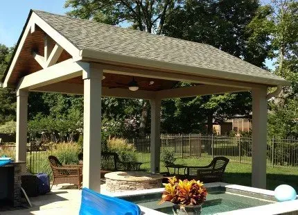 Covered patio with a fire pit, seating, and a pool in a backyard setting.