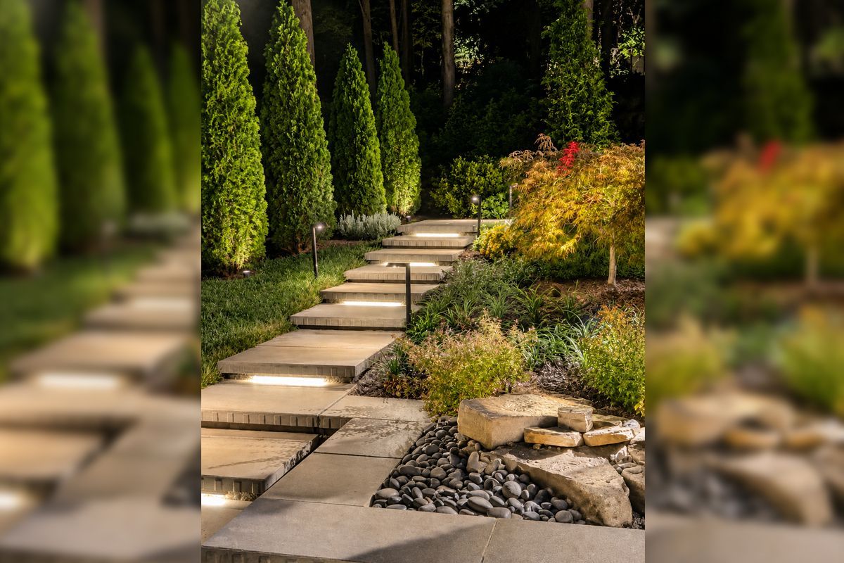 Stone garden path through tall green shrubs with yellow flowers and a small rock border