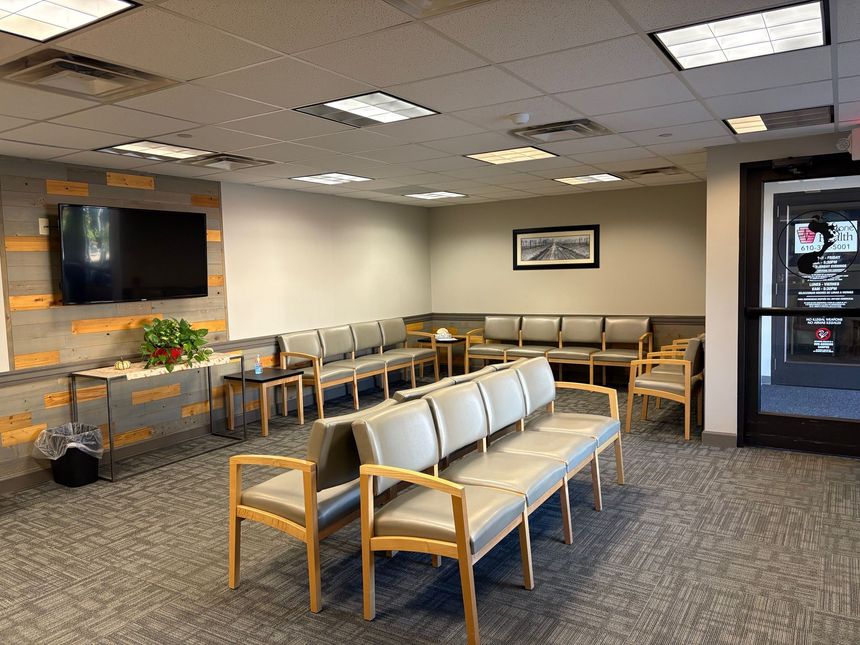 A waiting room with lots of chairs and a flat screen tv.