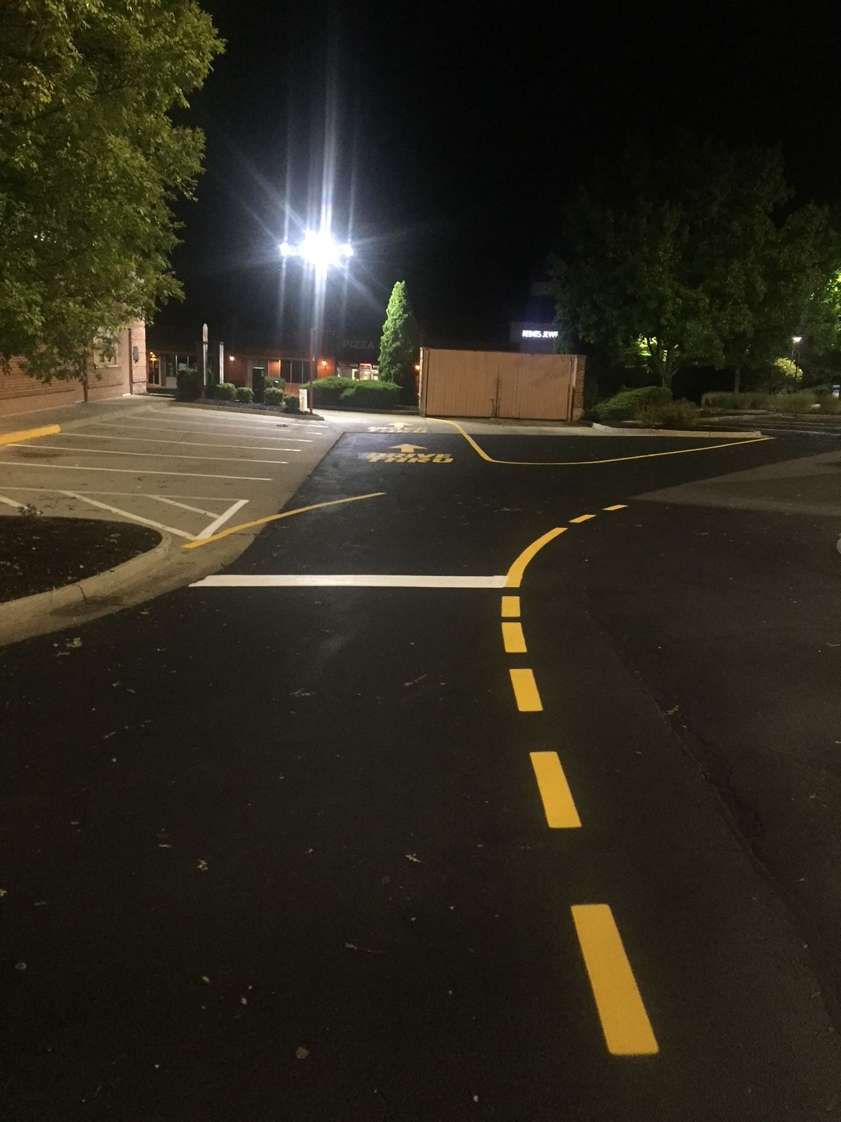 a parking lot at night with yellow lines on the road