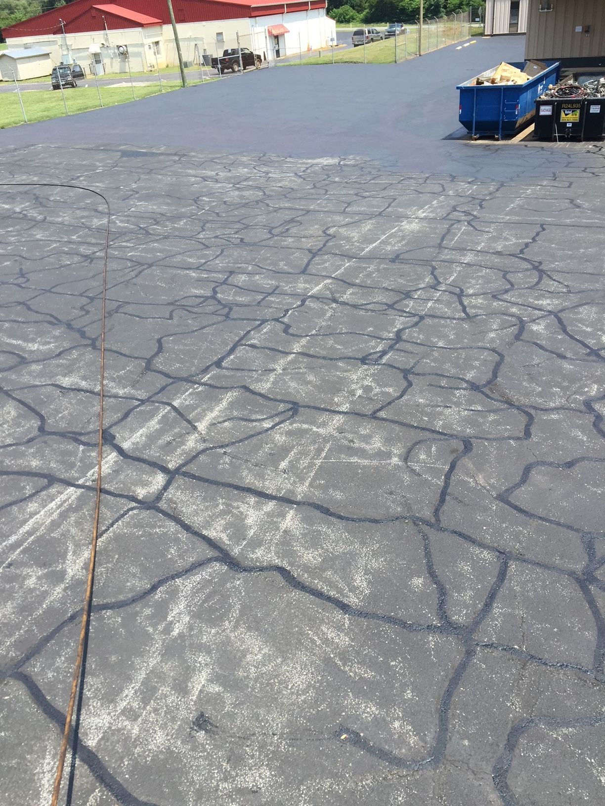 a concrete driveway with a blue dumpster in the background