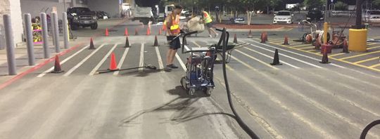 a man is using a machine to seal a crack in a parking lot
