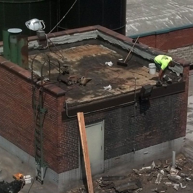 A man is working on the roof of a brick building