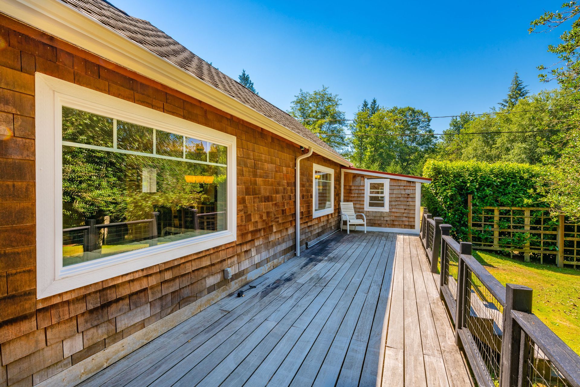 Wooden house with a deck overlooking a yard, sunny day.