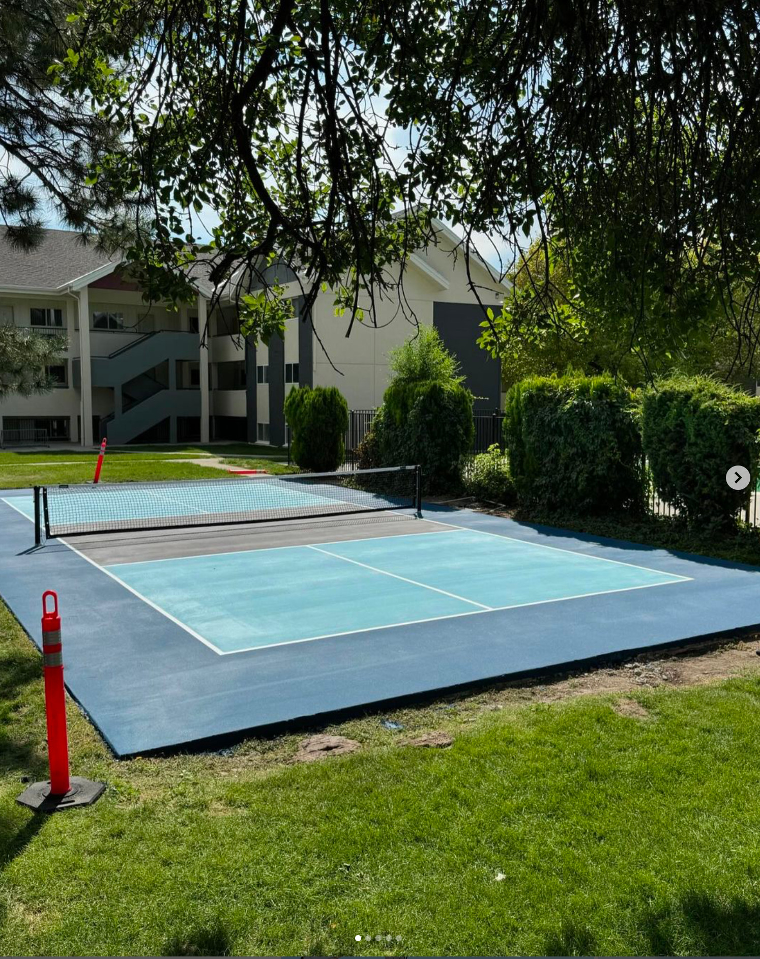 A blue tennis court with a red cone in front of it
