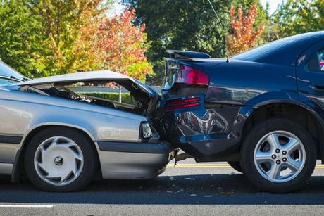 Two cars are involved in a car accident on the side of the road.
