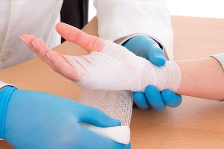 A doctor is wrapping a patient 's hand with a bandage.