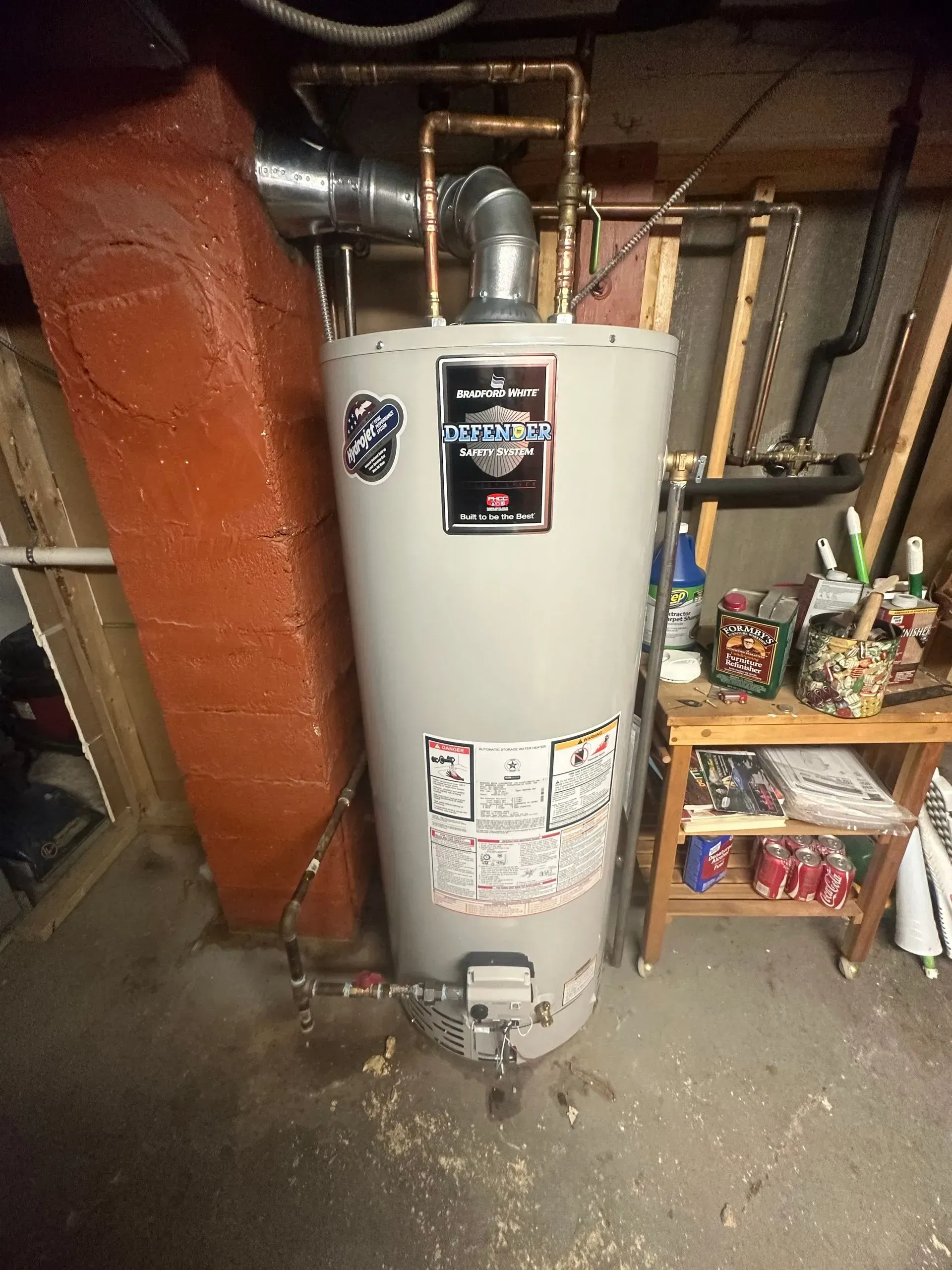 A water heater in a basement setting, with copper pipes and vent.