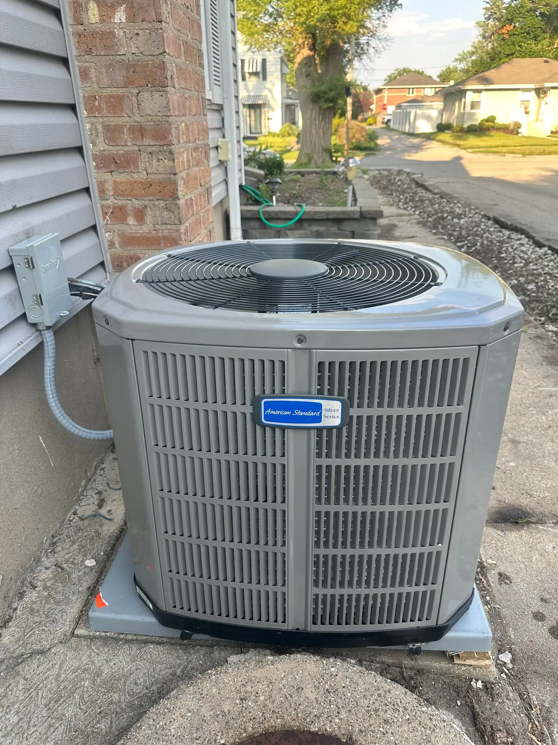 Gray air conditioning unit outside a house on a concrete pad.