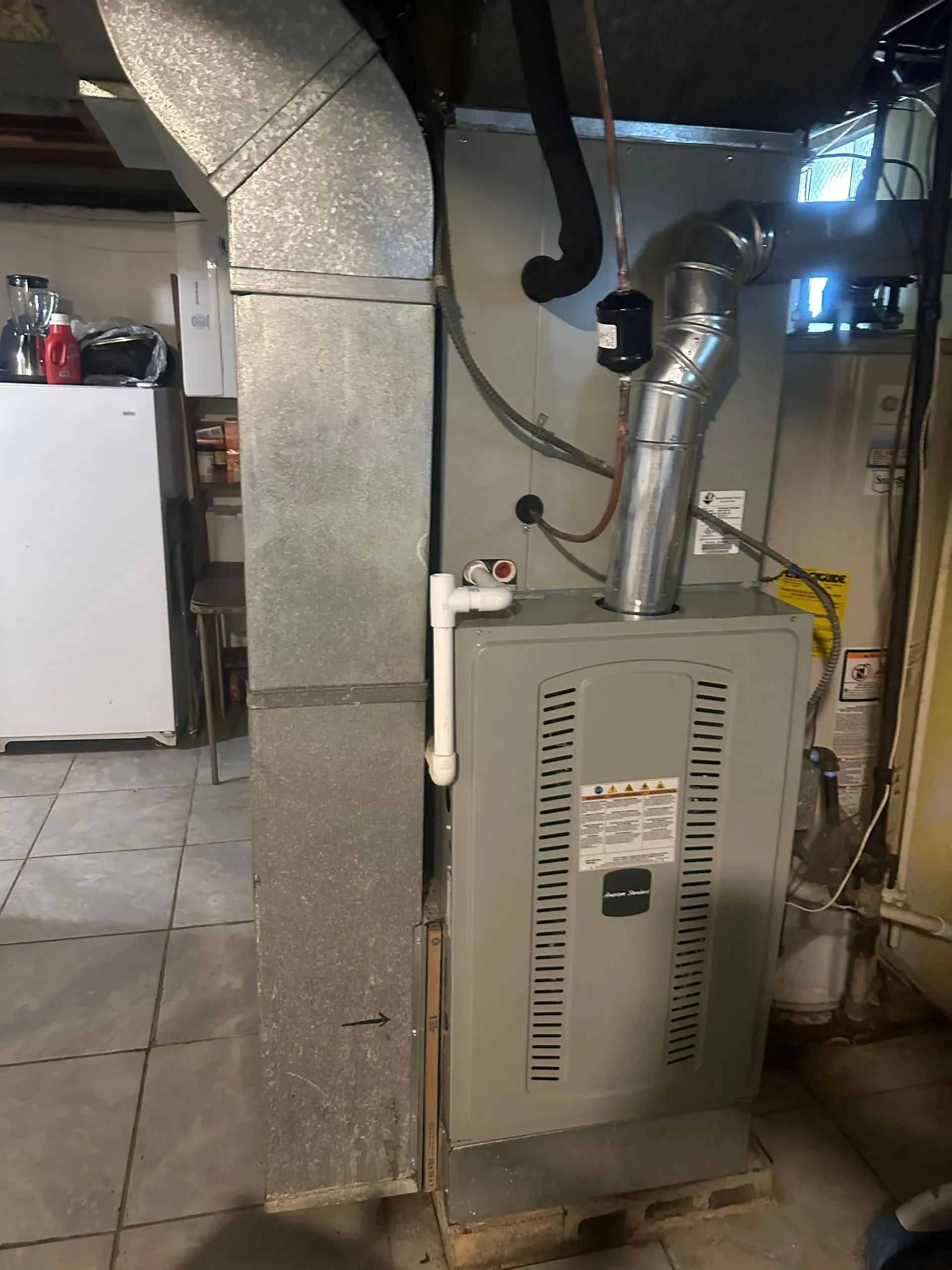 Furnace unit with attached ductwork in a basement. Gray, white, and silver.