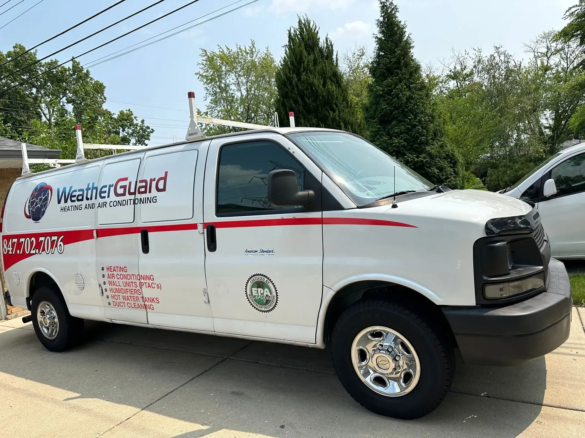 White WeatherGuard service van with red stripe, parked in front of a house.