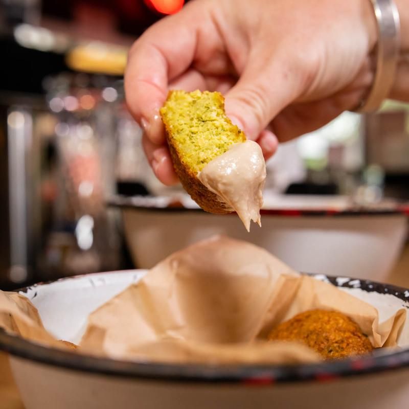 A person is dipping a piece of food into a bowl of food.