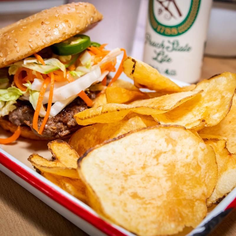 A hamburger sitting on top of a plate of potato chips