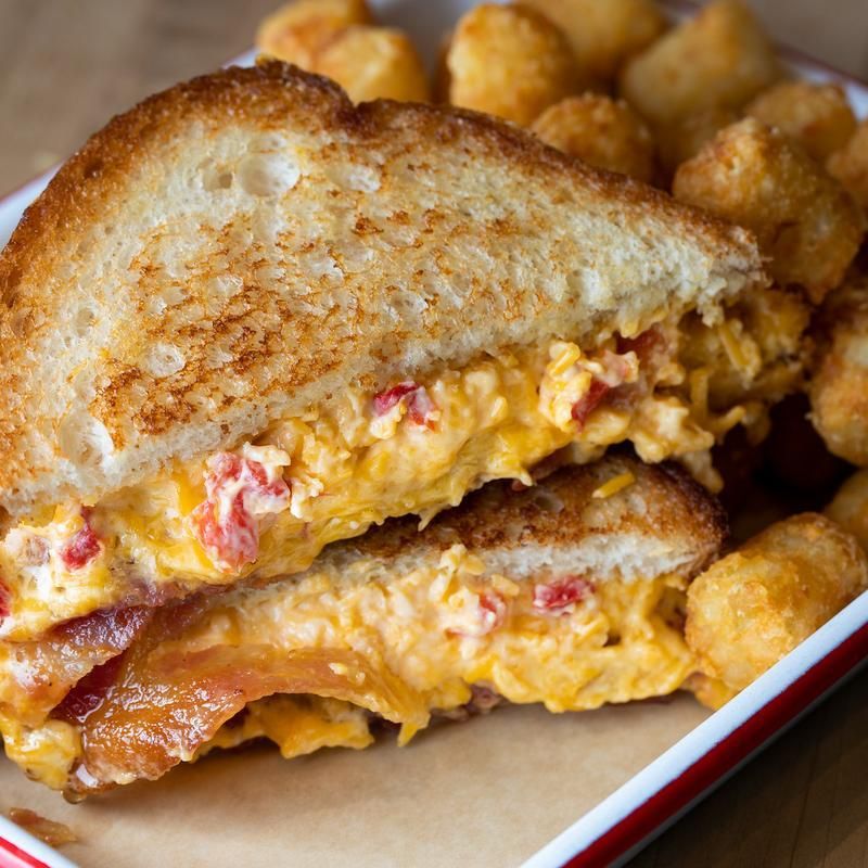 A close up of a grilled cheese sandwich on a plate with french fries.