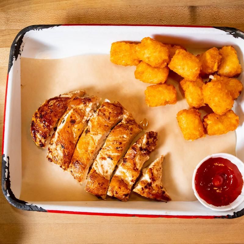 A tray of chicken and potato tots with ketchup