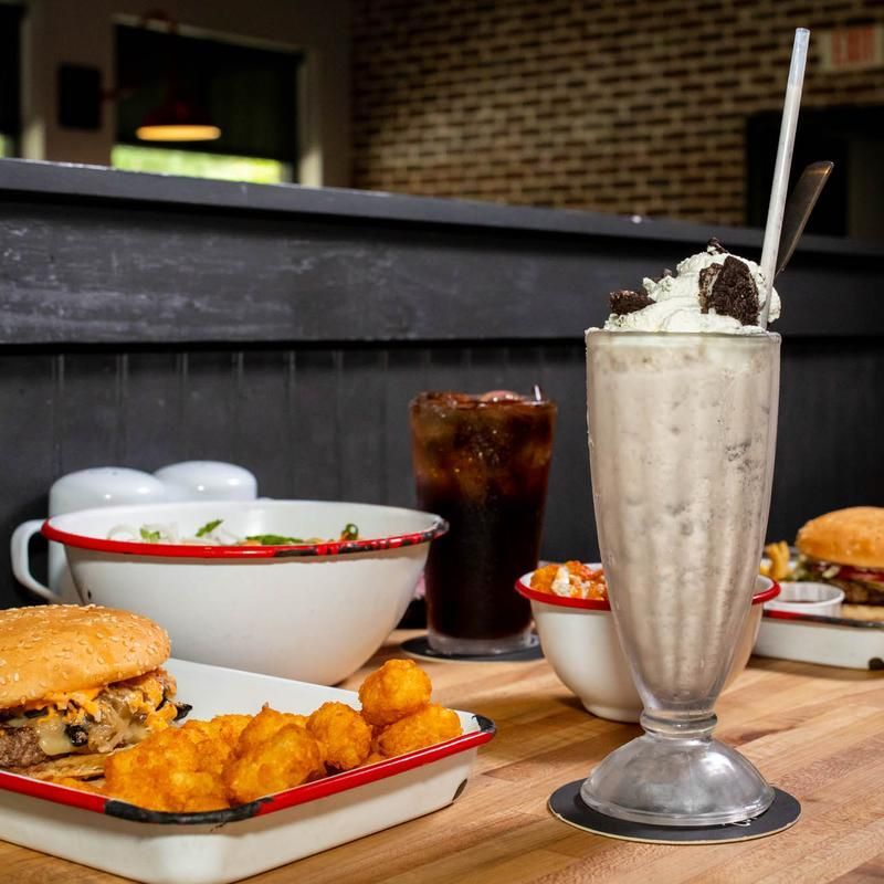 A table with a milkshake and a hamburger on it