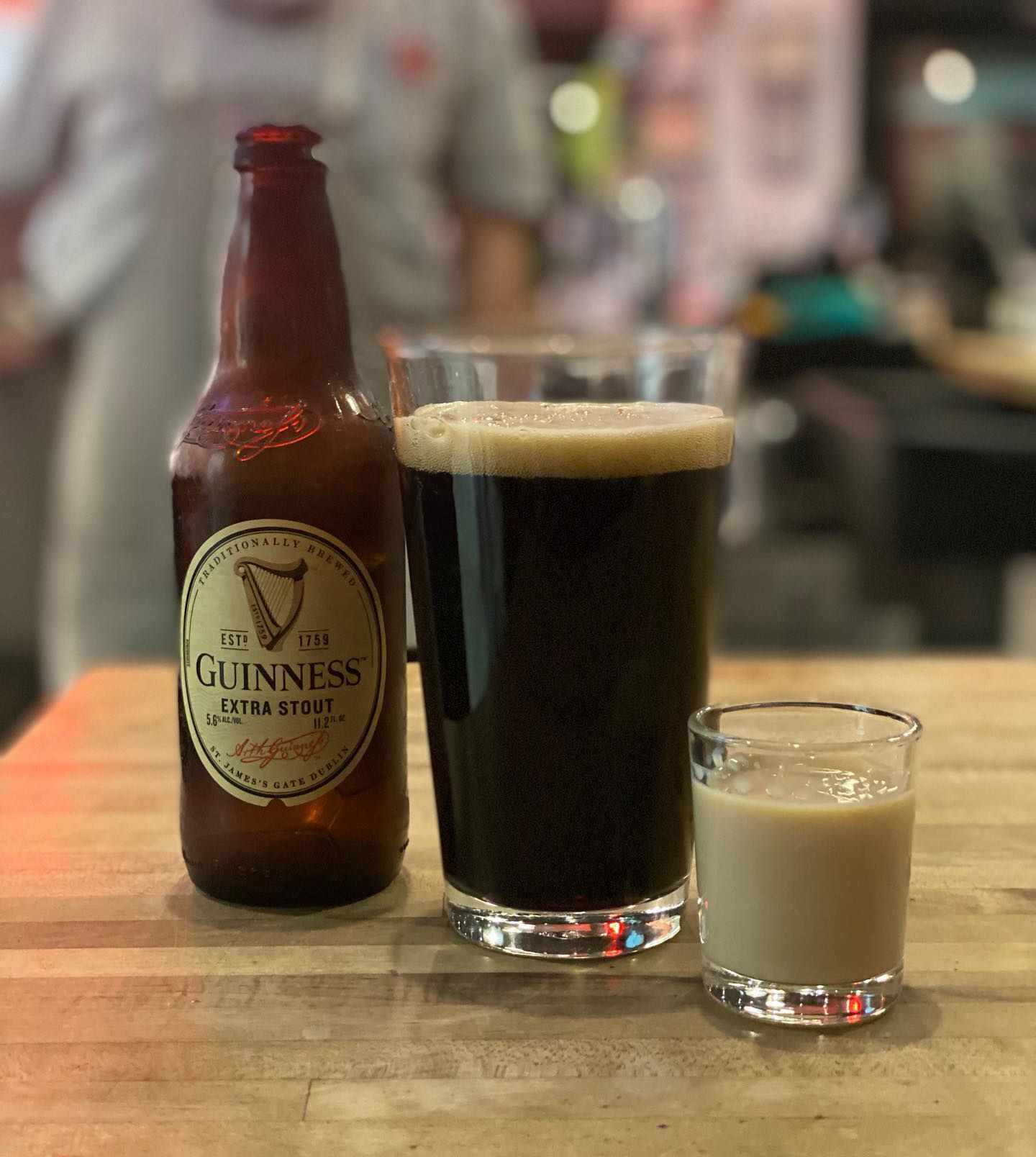 A bottle of guinness sits next to a glass of beer