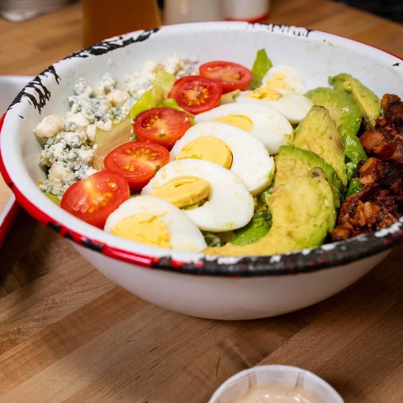 A bowl filled with eggs avocado tomatoes and blue cheese