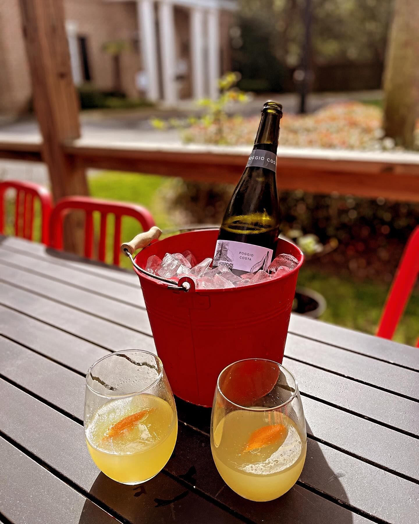 A bucket of ice and two glasses of wine on a table.